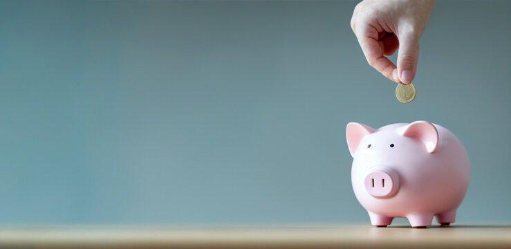 A piggy bank and a hand holding a coin. The image represents saving and inflation. Neutral background. Ideal as a banner or header. Space for text. Copy space and blank text. 