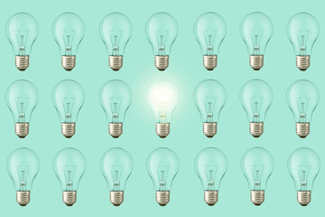 Lots of extinguished bulbs and one creative glowing bulb light on a pastel green background, view from above. Think different, creative idea. Fresh Thought Generator