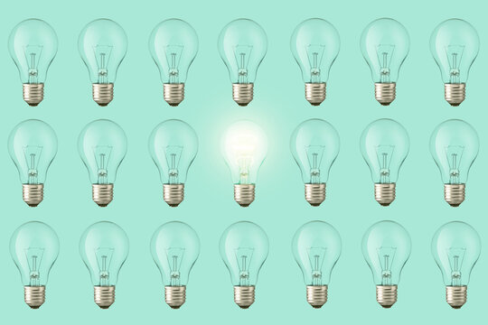 Lots of extinguished bulbs and one creative glowing bulb light on a pastel green background, view from above. Think different, creative idea. Fresh Thought Generator © alonesdj