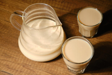 Coffee with milk in coffee pot and two thin espresso cups on wooden background
