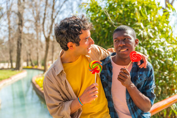 Multiethnic gay male couple eating a lollipop, lgbt concept, romantic fun