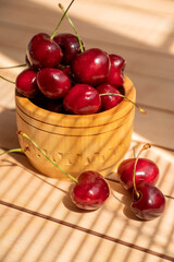 ripe sweet cherries in wooden bowl in sunlight