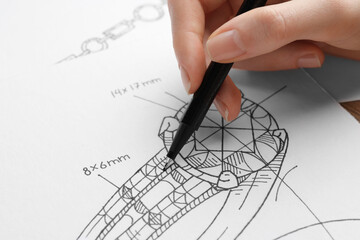 Jeweler drawing sketch of elegant ring on paper, closeup