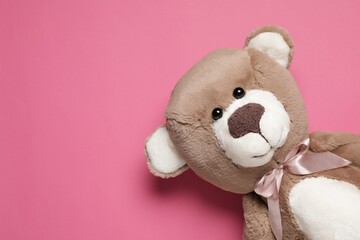 Cute teddy bear on pink background, top view. Space for text