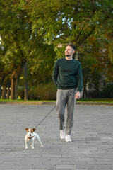 Man with adorable Jack Russell Terrier on city street. Dog walking