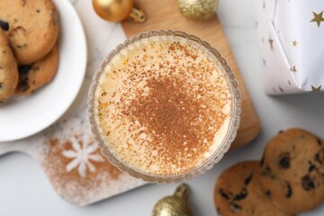 Glass of delicious eggnog with cinnamon on white table, flat lay