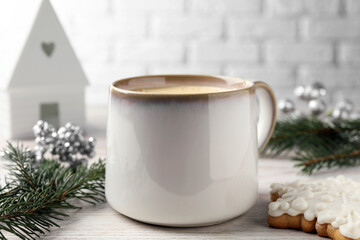 Fototapeta na wymiar Cup of delicious eggnog, fir branch and cookie on wooden table, closeup