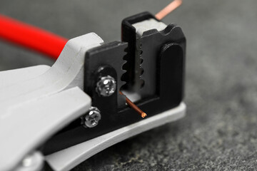 Cutters and stripped wire on light gray textured table, closeup