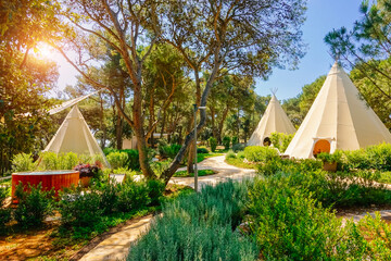 An outdoor relaxation area with teepee tents surrounded by lush vegetation. Croatia, Europe.