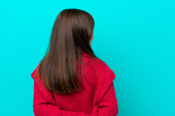 Little caucasian girl isolated on blue background in back position and looking back