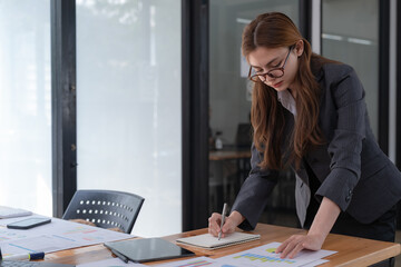 businesswoman writing business papers at a desk in a modern coworking office. copy space