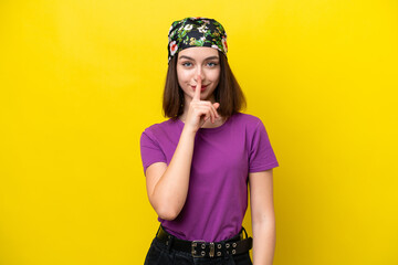 Young Ukrainian woman isolated on yellow background showing a sign of silence gesture putting finger in mouth