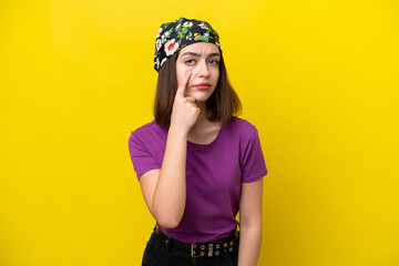Young Ukrainian woman isolated on yellow background showing something