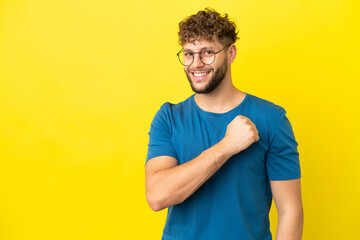 Young handsome caucasian man isolated on yellow background celebrating a victory