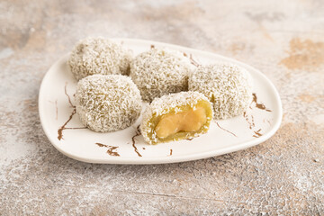 Japanese rice sweet buns mochi filled with pandan jam on brown concrete, side view.