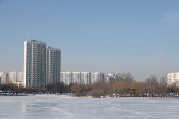 Landscapes in the park with melting snow, puddles and ice in spring. Residential buildings and...