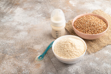 Powdered milk and buckwheat baby food mix, on brown concrete, side view, copy space