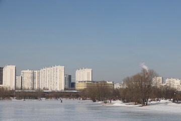Fototapeta premium Landscapes in the park with melting snow, puddles and ice in spring. Residential buildings and spring landscapes of Butovo, Moscow, thawed patches, March 2023.