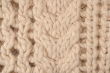 A fragment of beige knitted fabric, knitted from white sheep wool.