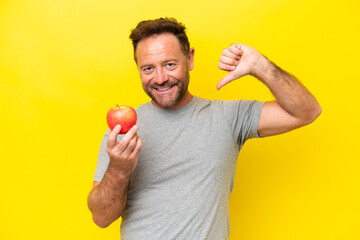 Middle age caucasian man with an apple isolated on yellow background proud and self-satisfied