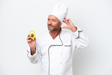 Chef man holding an avocado isolated on white background having doubts