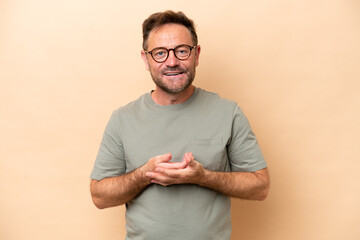 Middle age caucasian man isolated on beige background laughing