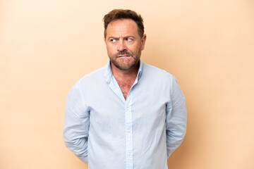 Fototapeta premium Middle age caucasian man isolated on beige background having doubts while looking up