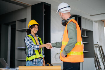 Construction team shake hands greeting start new project plan behind yellow helmet in office center to consults about their building project..