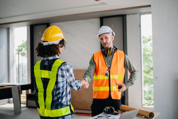 Construction team shake hands greeting start new project plan behind yellow helmet in office center to consults about their building project..