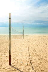 Beach volleyball net on a golden sand beach with turquoise sea waters and bright blue sunny sky