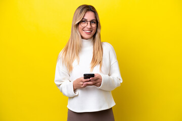 Young Uruguayan woman isolated on yellow background sending a message with the mobile