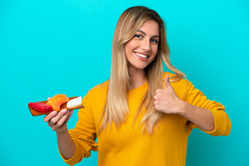 Young Uruguayan woman holding sashimi isolated on blue background giving a thumbs up gesture