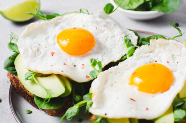 Avocado Sandwich with Fried Egg, Spinach and Green Sprouts, Healthy Breakfast or Snack on Bright Background