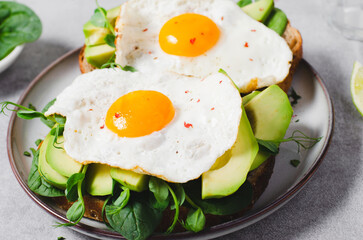 Avocado Sandwich with Fried Egg, Spinach and Green Sprouts, Healthy Breakfast or Snack on Bright Background