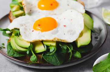 Avocado Sandwich with Fried Egg, Spinach and Green Sprouts, Healthy Breakfast or Snack on Bright Background