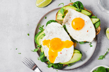 Avocado Sandwich with Fried Egg, Spinach and Green Sprouts, Healthy Breakfast or Snack on Bright Background