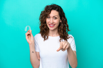 Fototapeta premium Young caucasian woman holding a envisaging isolated on blue background points finger at you with a confident expression
