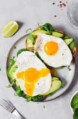 Avocado Sandwich with Fried Egg, Spinach and Green Sprouts, Healthy Breakfast or Snack on Bright Background