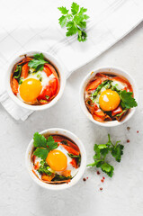 Baked Eggs with Bacon, Tomatoes, Spinach and Herbs on Bright Background, Healthy Breakfast or Snack