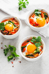 Baked Eggs with Bacon, Tomatoes, Spinach and Herbs on Bright Background, Healthy Breakfast or Snack