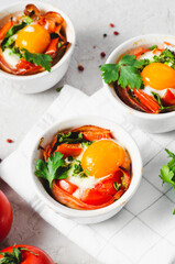 Baked Eggs with Bacon, Tomatoes, Spinach and Herbs on Bright Background, Healthy Breakfast or Snack