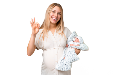 Young pretty pregnant woman with her newborn baby over isolated chroma key background showing ok sign with fingers