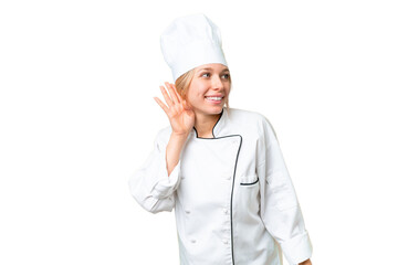 Young chef woman over isolated chroma key background listening to something by putting hand on the ear