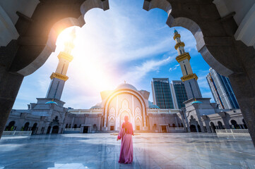 Naklejka premium Woman dressed in islamic clothing in Masjid Wilayah Persekutuan (Federal Territory Mosque), and sunlight in Kuala Lumpur, Malaysia.