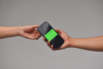 Two people handing smartphones to each other for communication purposes.