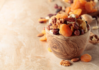 Obraz na płótnie Canvas Dried fruits and nuts on a beige ceramic table.