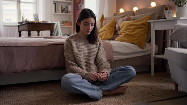 Sad teenage girl sitting on the floor.