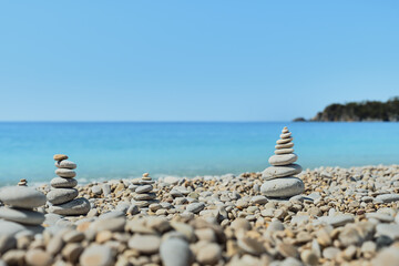 Fototapeta na wymiar Pyramid stones balance on the beach against the background of the sea and the sky. Object in focus, blurred background, idea of a vacation or retweet by the sea