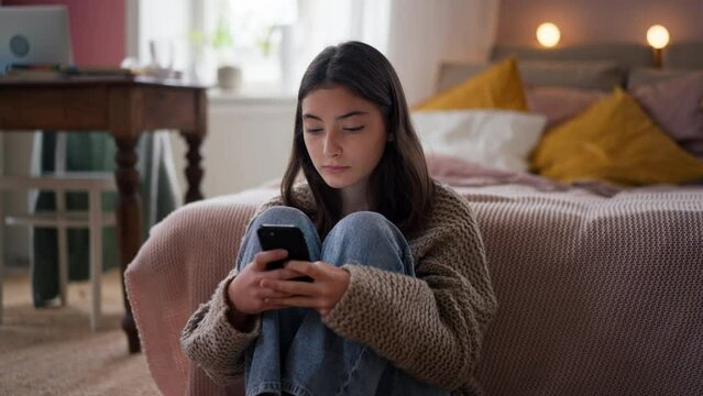 Young teenage girl srolling her smartphone in the room.