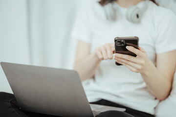 Happy woman holding apple and listening to music sitting on sofa in living room at home
